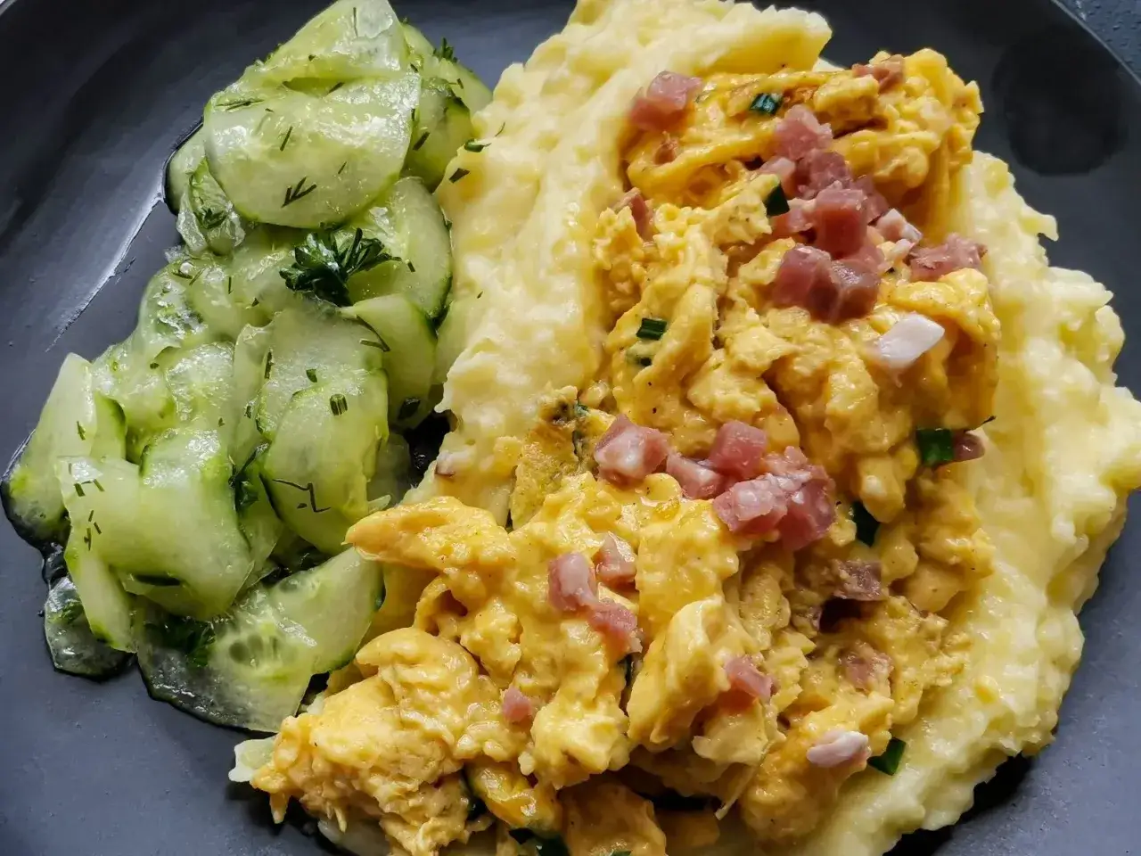 Pyszne puree ziemniaczane z jajecznicą i boczkiem, obok sałatka z ogórków. Czy puree ziemniaczane jest zdrowe? Zależy od dodatków!
