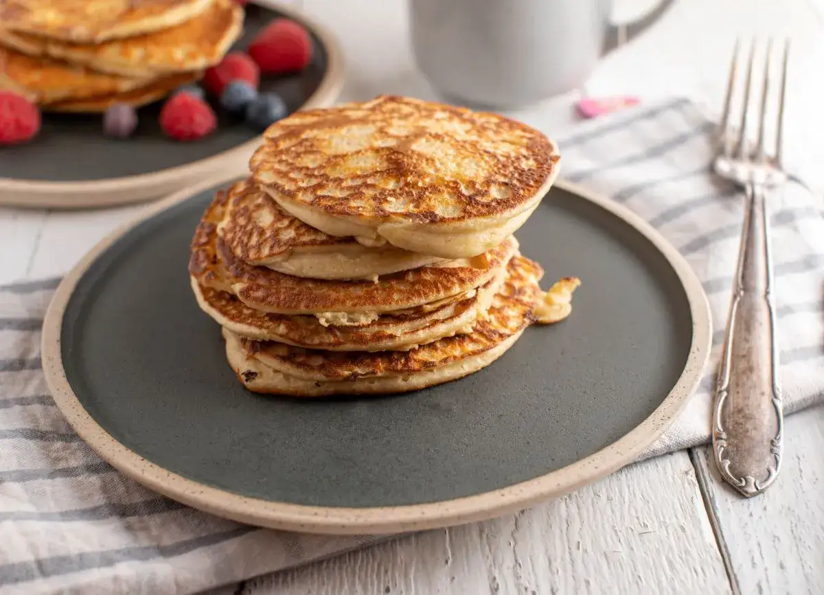 Stos puszystych pancakes na talerzu, ozdobiony malinami i borówkami. Czy pancakes są lekkostrawne? Zależy od składników!