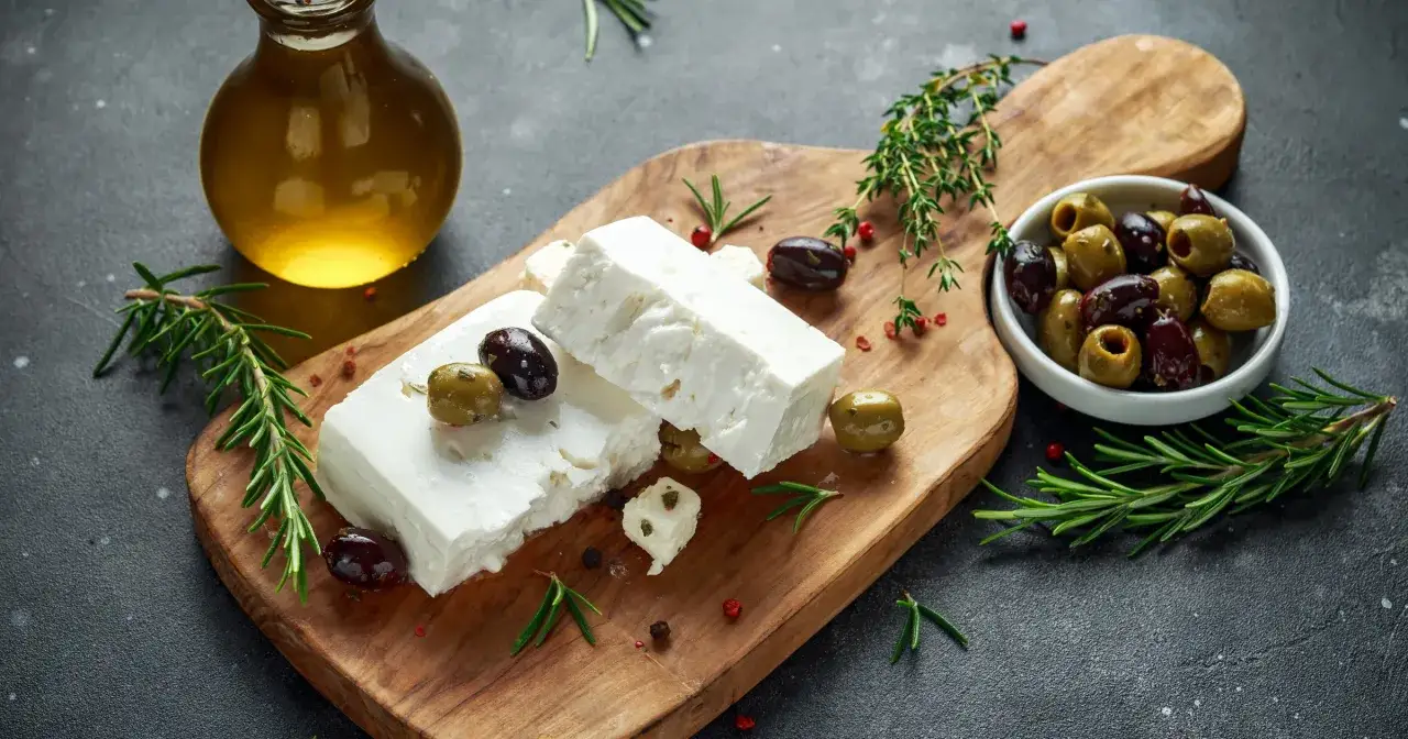 Ser feta z oliwkami i rozmarynem na desce. Czy feta jest zdrowa? Tak, w umiarkowanych ilościach, jako część zbilansowanej diety.