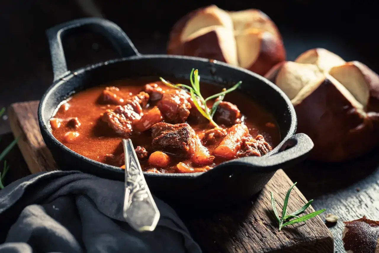 Gęsty, aromatyczny gulasz w żeliwnej patelni, idealny do podania z pieczywem. Dowiedz się, jak zagęścić gulasz bez mąki, by uzyskać idealną konsystencję.