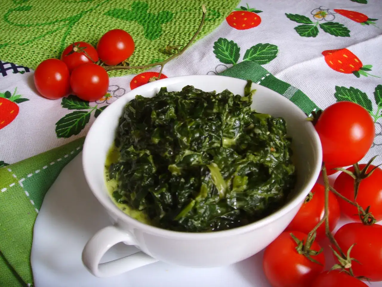 Jak usmażyć szpinak? Aromatyczny, zielony szpinak w kremowym sosie, podany z pomidorkami koktajlowymi.