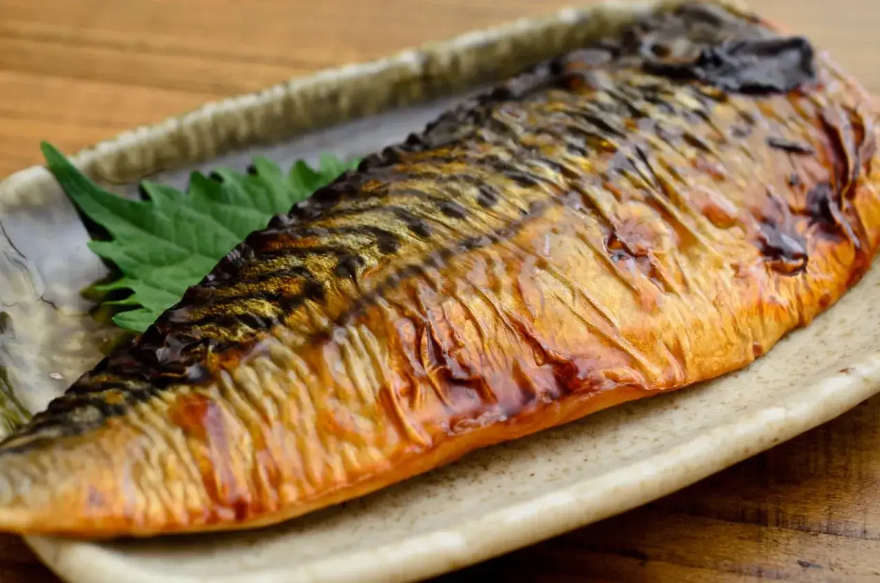 Pieczona makrela na talerzu, z zielonym liściem. Czy makrela jest zdrowa? Tak, to bogactwo kwasów omega-3!