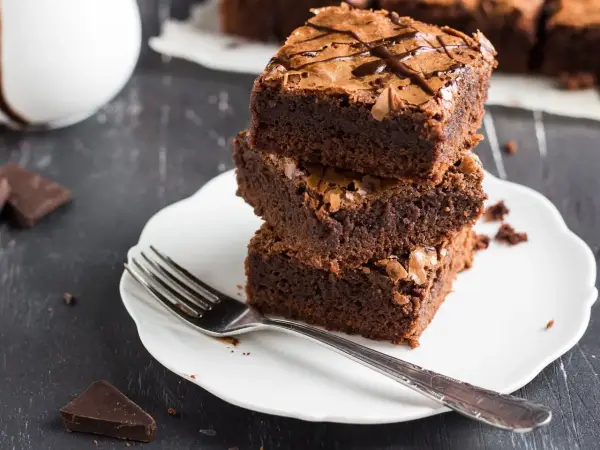 Stos puszystych brownie na talerzyku, idealne na zdrowe przekąski. Szukasz ciasta fit przepisy? Oto one!